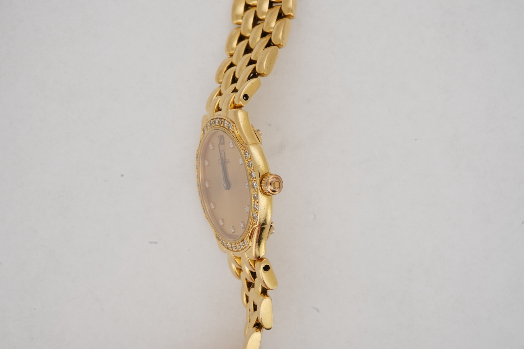 A lady's recent 18ct gold Omega quartz dress wrist watch, with diamond dot markers and diamond set bezel